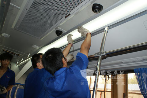 工人们汗流浃背地为该批气-电混合动力公交车铺设灯管